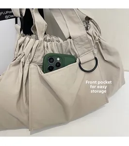 Close-up of beige canvas handbag showing a front storage pocket with a smartphone inside