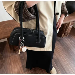 Detail of black Boston bag with white contrast stitching and baseball bat charm