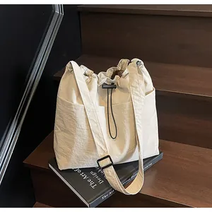 Détail du sac seau beige en nylon avec textures plissées et bandoulière réglable