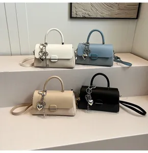 Détails de quatre sacs bandoulière en tissu texturé avec breloques cœur en divers coloris