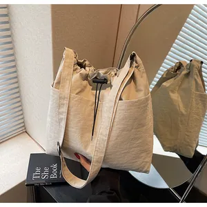 Détail du sac seau beige en nylon avec poches frontales et fermeture à cordon coulissant