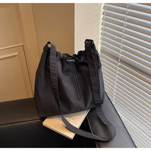 Détail du sac bandoulière en nylon noir avec texture plissée et cordons de serrage