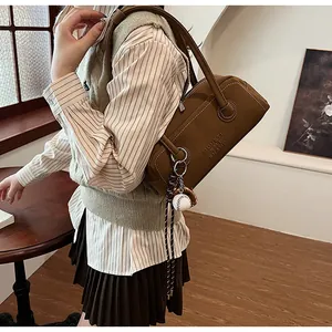 Detailed texture of brown pebble leather bowling bag with baseball charm and stitch detail