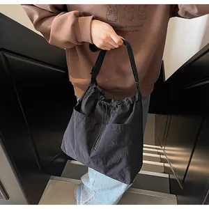 Détail du sac seau en nylon noir avec cordon de serrage et poches avant pratiques