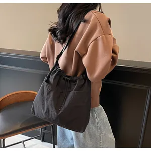 Détail d'un sac à bandoulière en nylon noir avec cordon de serrage et doubles poches
