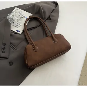 Detail of dark brown leather bowling bag showing contrast white stitching and handles