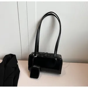 Dettaglio borsa a spalla in pelle lucida nera con doppia tracolla e mini pochette