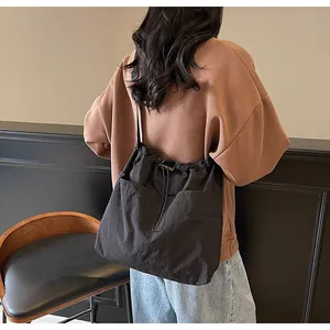 Détail d'un sac seau en nylon noir avec deux poches avant porté par une personne