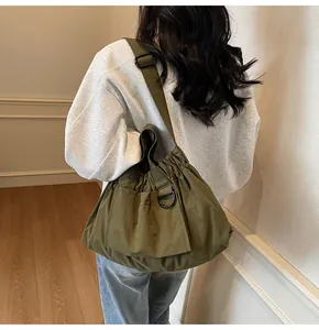 Olive green nylon shoulder bag with drawstring detail and side pockets on model