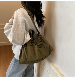 Olive green shoulder bag in textured nylon with wide strap and minimalist pleated design
