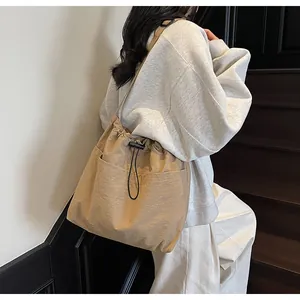 Détail du sac seau en nylon kaki avec cordon de serrage et poches avant sur mannequin