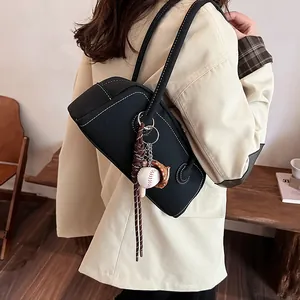 Retro black leather bowling bag with contrast stitching and baseball charm on shoulder