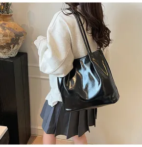 Detail of a black glossy leather tote bag showing spacious capacity and soft texture