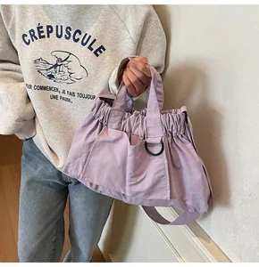 Detail of light purple nylon handbag with drawstring closure and black D-ring buckle