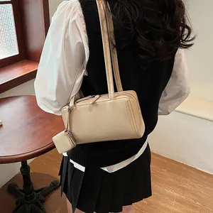 Elegante borsa sottobraccio beige con mini pochette indossata da modella chic