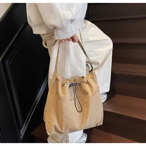 Détail du sac à bandoulière en nylon beige avec cordon de serrage et poches latérales