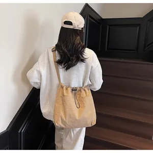 Détail d'un sac seau en nylon kaki avec cordon de serrage et grandes poches avant