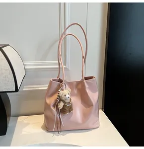 Close-up of soft pink leather tote bag with stylish bear pendant and shoulder straps