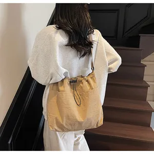 Détail du sac à bandoulière en nylon kaki avec cordon de serrage et poches frontales