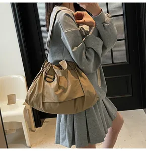 Detail of khaki nylon tote bag showing drawstring closure and spacious texture on shoulder