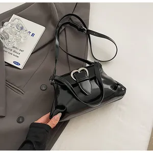 Détail d'un sac en cuir verni noir brillant avec une boucle métallique en forme de cœur argent