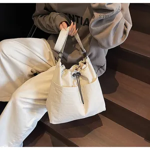 Détail du sac bandoulière en nylon beige avec cordon de serrage, texture plissée et fermoir