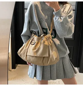 Detail view of khaki crossbody bag with drawstring closure and wide strap on model