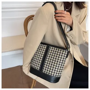 Detail of houndstooth bucket bag with contrast stitching and golden hardware