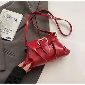 Détail du sac bouffant en cuir verni rouge avec une boucle métallique en cœur