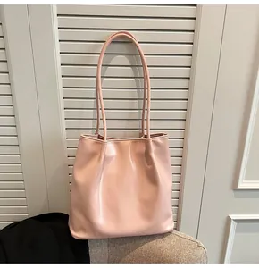 Close-up of pink soft leather tote bag on a grey chair showing smooth matte texture