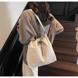 Détail d'un sac à bandoulière en nylon beige à cordon avec grande poche frontale
