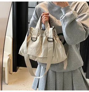 Detail of light beige shoulder bag featuring drawstring closure and adjustable wide strap