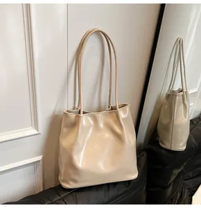 Detail shot of beige glossy leather tote bag showing fine pleats and long shoulder straps