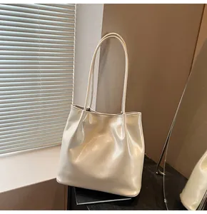 Detail of a creamy glossy leather tote bag with dual straps in a soft lighting scene