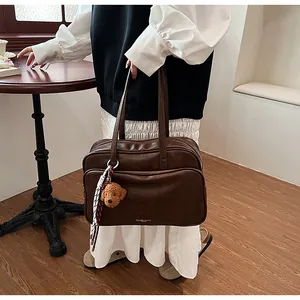 Detail of vintage brown leather Boston bag with plush bear charm and brand logo