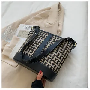 Detail of houndstooth tote bag with black leather trim and contrast stitching