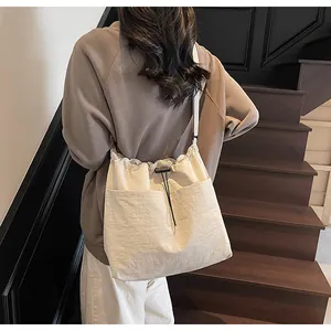 Détail du sac seau blanc cassé avec cordon de serrage, texture plissée et poche frontale