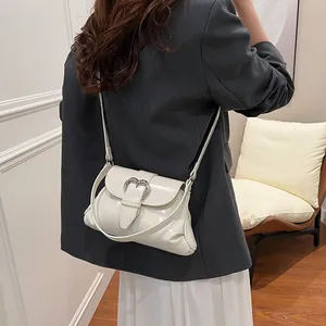 Sac hobo minimaliste en cuir PU beige brillant avec boucle cœur argentée porté par un modèle