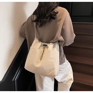 Vue détaillée du sac seau en nylon beige avec fermeture à cordon et doubles poches avant