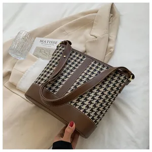 Detail of houndstooth tote bag with brown leather trim and stylish lifestyle props