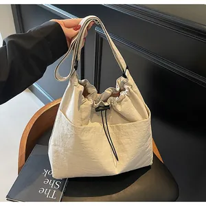 Détail du sac seau en nylon beige avec fermeture à cordon et texture plissée élégante