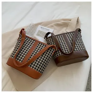 Detail view of houndstooth canvas and leather stitching on retro bucket bags with straps