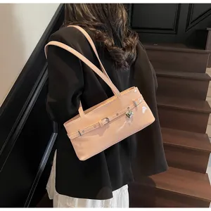 Détail du sac sous le bras en cuir verni rose avec breloque cœur et boucle