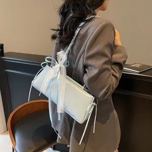 Light blue baguette bag with lace bow and silk scarf handle on grey blazer