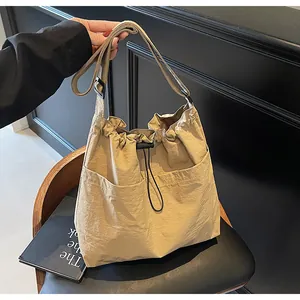 Gros plan du sac seau en nylon kaki avec plis à cordon et large bandoulière réglable