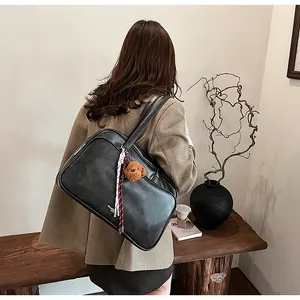 Detail of black faux leather Boston bag featuring a cute brown dog plush pendant accessory