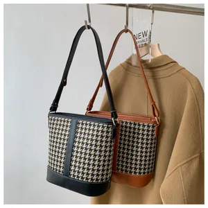 Classic houndstooth bucket bags in black and brown leather trim hanging on display hooks