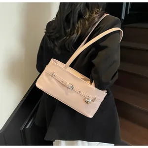Détail d'un sac sous le bras en cuir rose brillant avec pendentif cœur sur mannequin