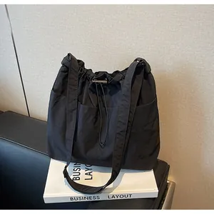 Détail du sac seau en nylon noir avec fermeture à cordon et poches plaquées sur le devant