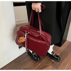 Detailed view of dark red Boston bag with cute bear charm and woven cord on model